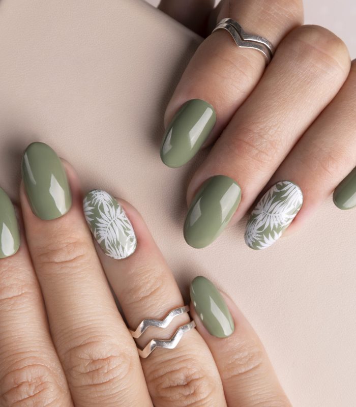 Beautiful womans hands with spring summer floral nail design. Trendy green color manicure close-up